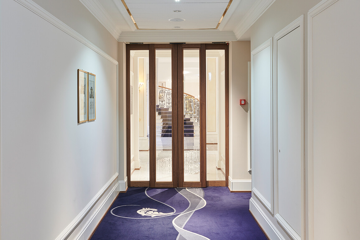 Automatische Schiebetür aus Holz und Glas als Hotelkorridor-Abschluss zu Lobby